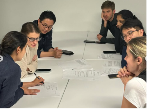 seven Internal Medicine Residents around a table looking and discussing paperwork