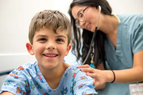 Boy smiling while nurse checks heartbeat