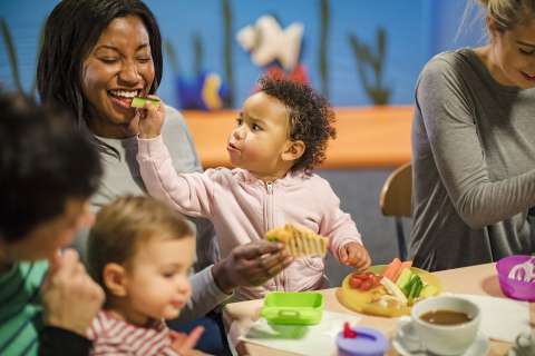 Child trying to feed mother vegetables