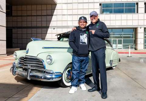 Louie Mejia smiling in front of classic car