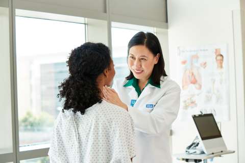 Doctor examining patient during clinic visit, hand on patient's shoulder