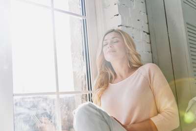 woman breathing while sitting next to a window