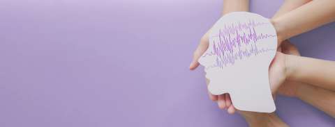 Adult and child hands holding encephalography brain paper cutout