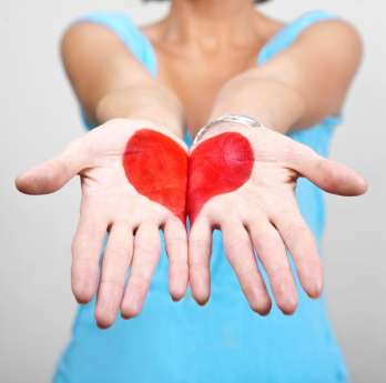 Woman holding out her hands with a heart painted on them