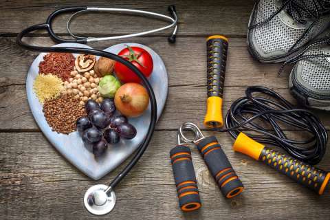 Heart shaped plate with fruits and veggies next to workout equipment