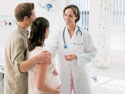Doctor speaking to pregnant woman and her husband in hospital room