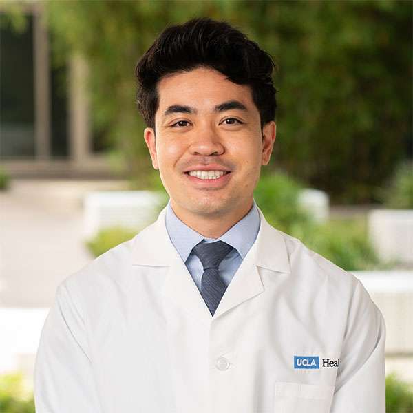 Jonathan Pham, PhD, smiling in white coat.