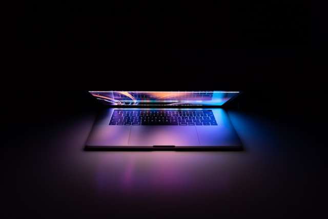 photo of half open laptop with bright screen in front of a black background