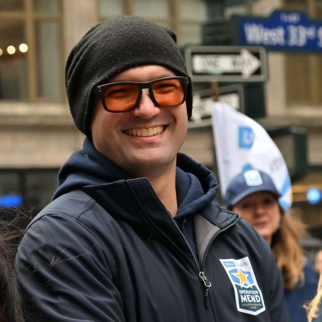 Buster Miscusi wearing a black beanie and navy Operation Mend jacket at the 2025 Veterans Day Parade in NYC.