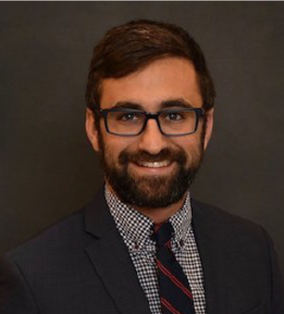 A smiling man with dark hair and glasses.