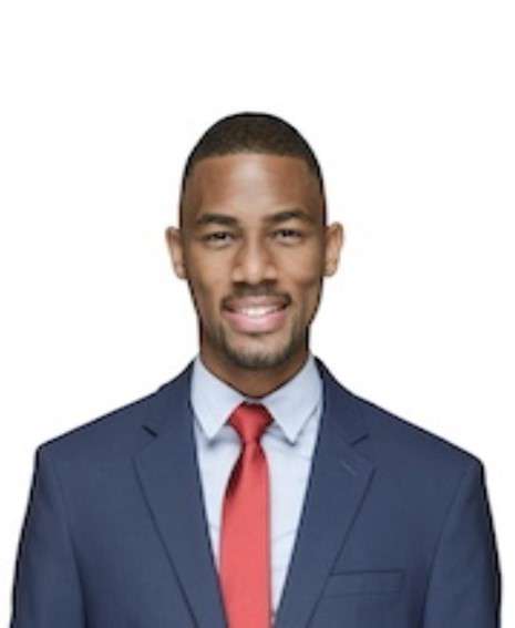 A smiling man wearing a blue suit and a red tie in front of a white background.
