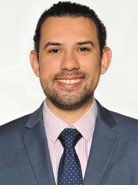 Dr. Brandon Agundez smiling in a grey suit