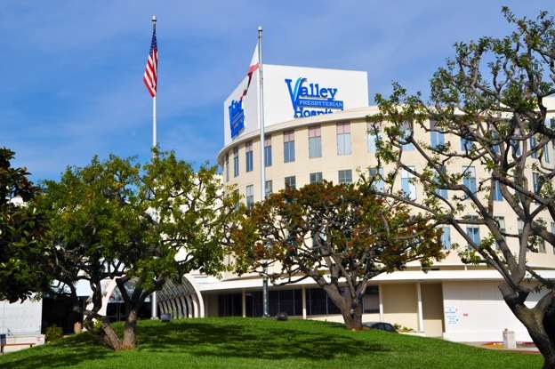 Multi-story building with "Valley" sign, American flag and trees