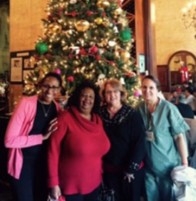 Four Faithful Central Bible Church members posing in front of a Christmas tree