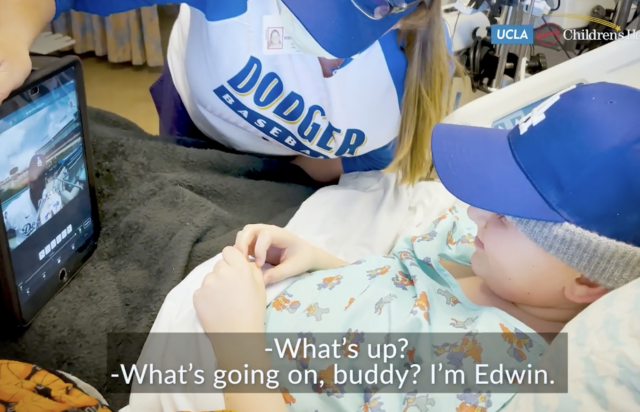 Pediatric patient in a hospital bed, using a robot to "run the bases" at Dodger Stadium