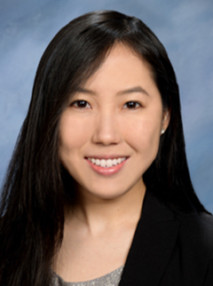 A smiling woman with dark hair and a black jacket.