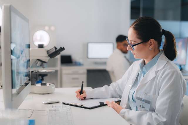 Woman scientist doing research and writing in laboratory for experiment