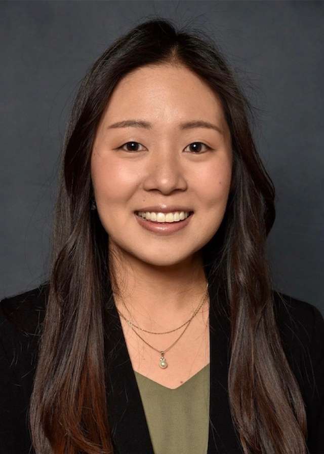 Smiling woman headshot with long dark hair against a dark background