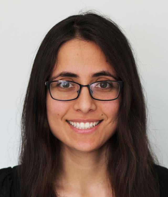 Headshot of smiling person with long dark hair and glasses.