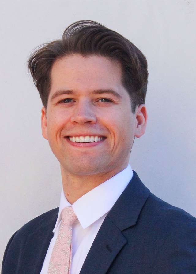 Smiling man in suit and tie against pale background