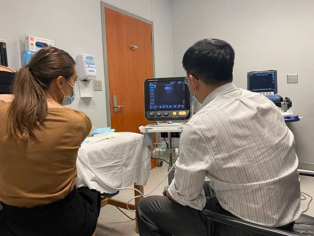 two doctors facing away from the camera looking at a monitor in a clinic space