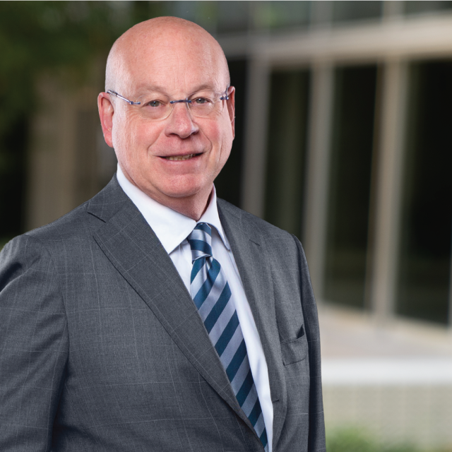 Dr. Michael Steinberg, wearing glasses and a dark suit with striped tie, smiling in a professional headshot.