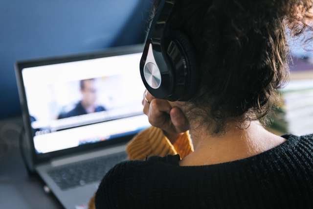 woman with headphones watching video on laptop