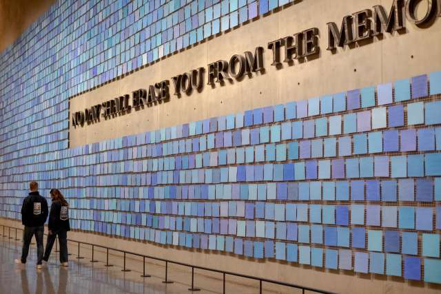A couple wearing Operation Mend jackets, viewing a wall at the 9/11 museum. 