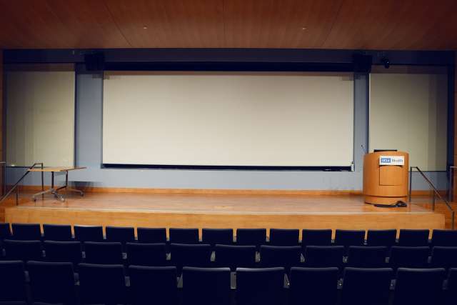 photo of an empty auditorium with the seats in the foreground and the stage and pulpit in the background