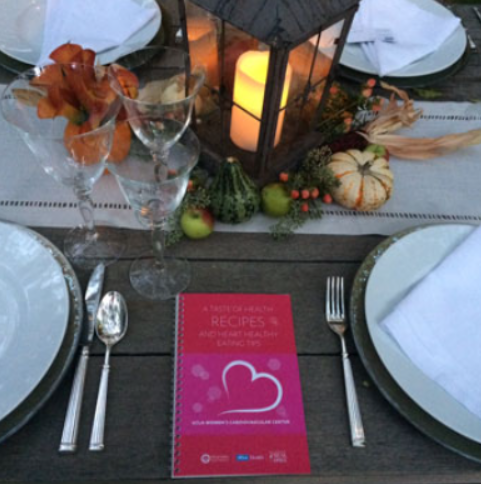 Table setup with a centerpiece, glasses, porcelain plates, and silverware. A taste of health event.