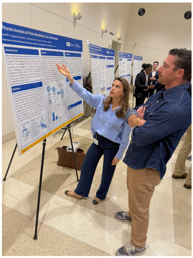 Woman pointing at research poster while explaining to an attentive man.