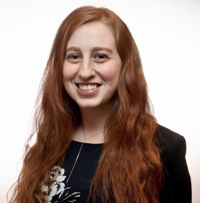 Alana Corre with long, wavy, auburn hair and a dark top.