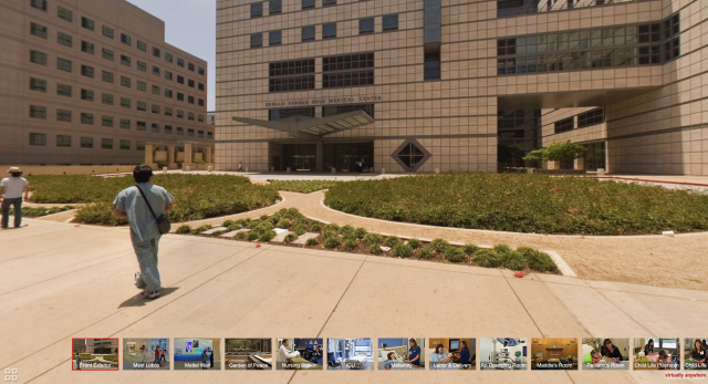A screenshot of the Ronald Reagan Medical Center Virtual Tour, displaying the entrance of the hospital with a healthcare worker in blue scrubs walking