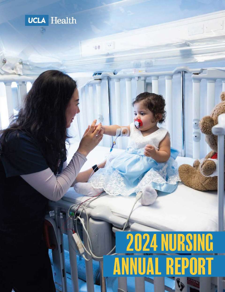 Nurse holding toddler's hand and smiling while child sits on a hospital bed