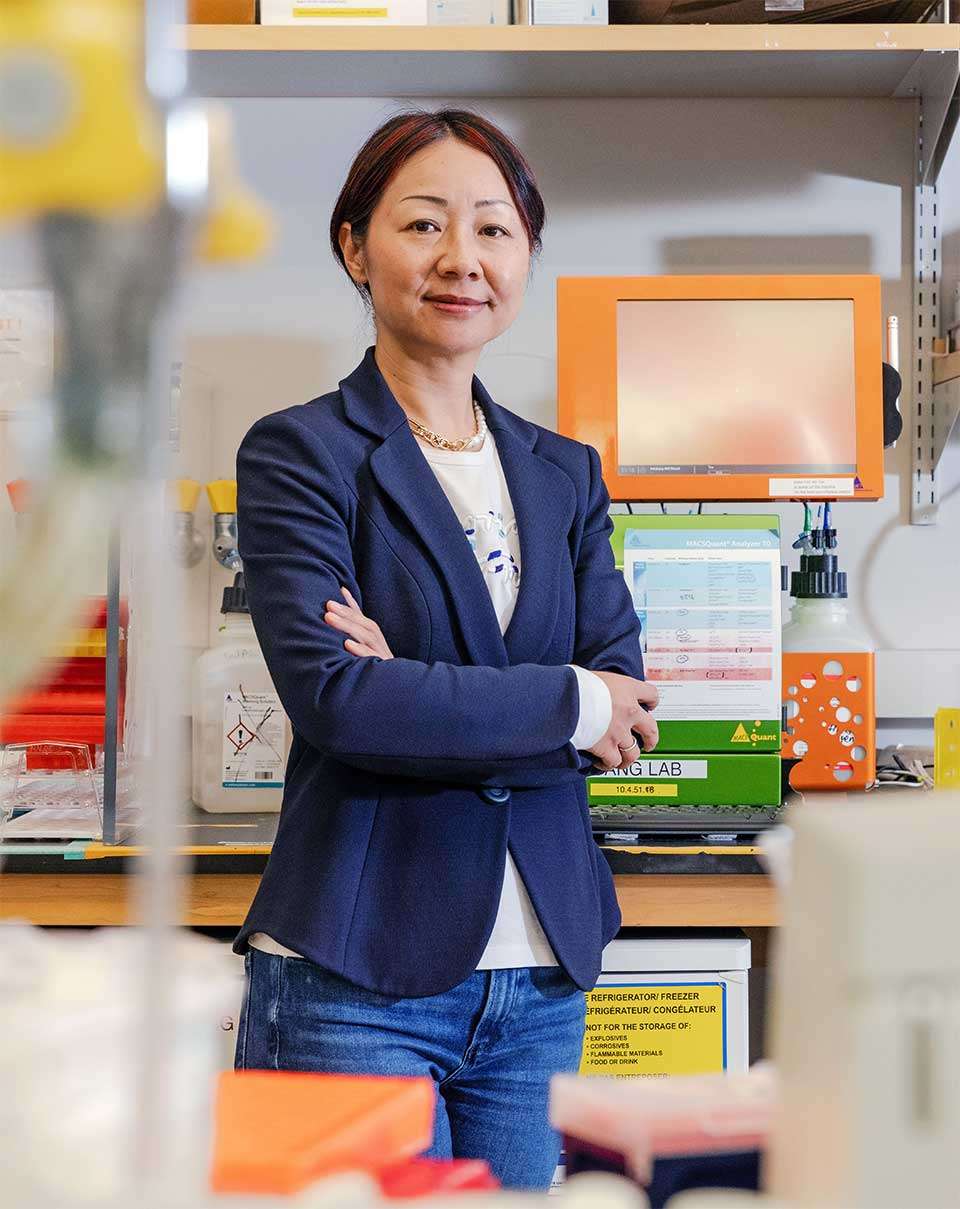 Dr. Lili Yang in a research lab, standing with arms crossed.