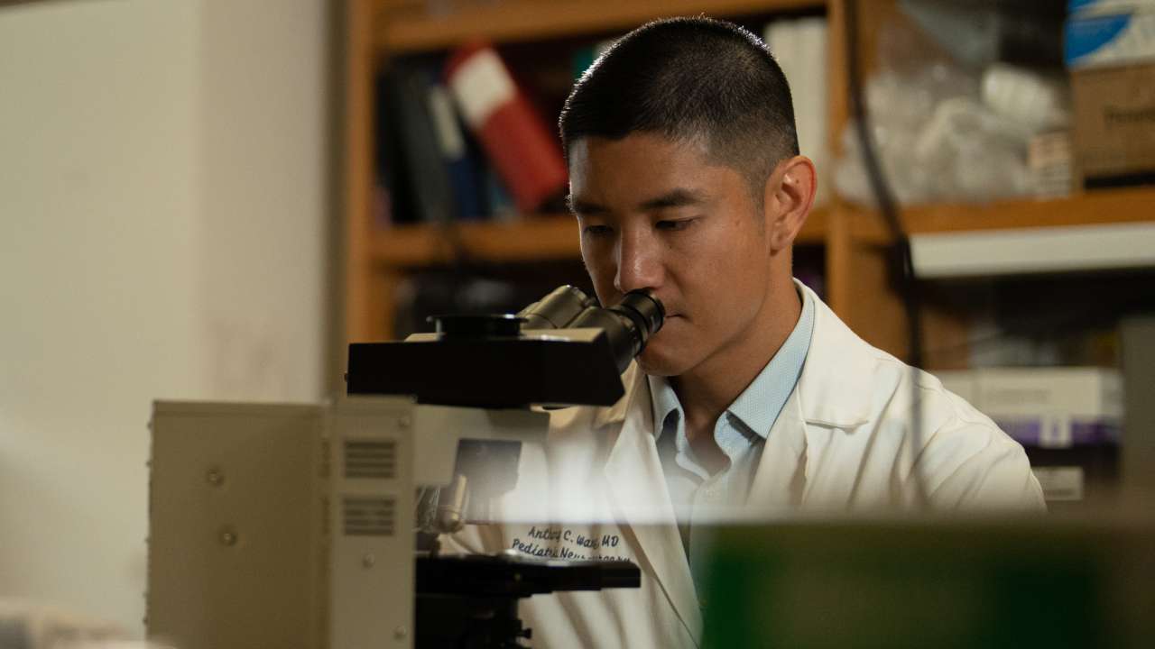 Dr. Anthony Wang looking into a microscope. 