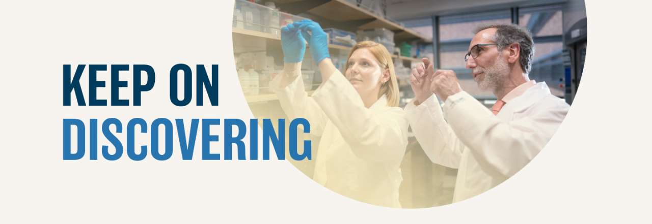 Male and female cancer researchers stand together in a lab working, with the words Keep on Discovering displayed over the image