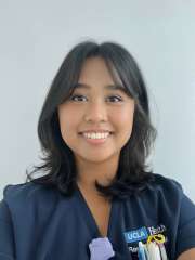 A headshot of Allison Bautista, a young woman with dark hair and a nose ring, smiling in a navy UCLA Health scrub top.