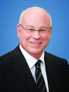 Dr. Michael Steinberg, wearing glasses and a dark striped suit, smiling in a professional headshot.