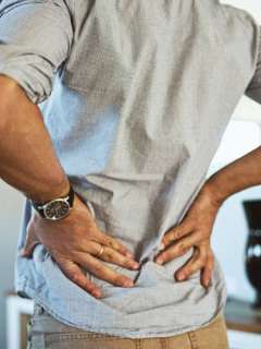 man with both of his hands on his lower back stretching