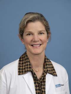 Joann G. Elmore, MD, MPH smiling in a white coat against a blue background