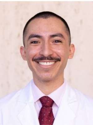 Smiling man wearing white coat and red tie, professional headshot