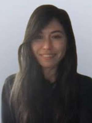 Smiling woman with long dark hair, headshot on plain light background.