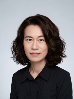 Person with wavy brown hair in a black collared shirt, facing the camera.