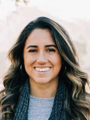 Smiling woman with long brown hair stands outdoors