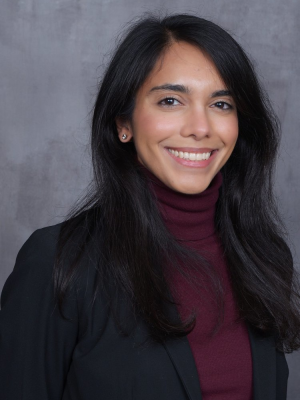 Head-and-shoulders portrait with face blurred, black blazer and burgundy turtleneck.