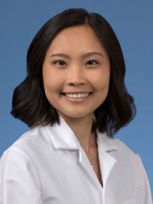 Head shot of Kristine Khieu in a white coat, smiling at camera