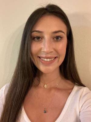 Smiling woman with long brown hair wearing two necklaces facing the camera