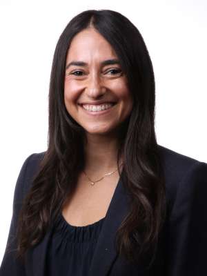 Professional headshot of woman in navy blazer and necklace