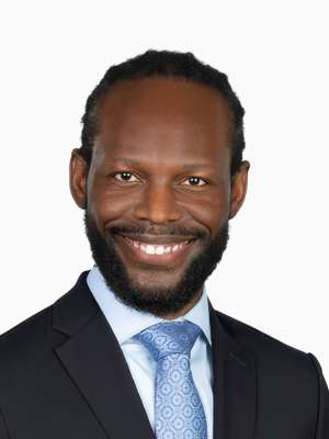 Smiling man in dark suit and light blue tie headshot